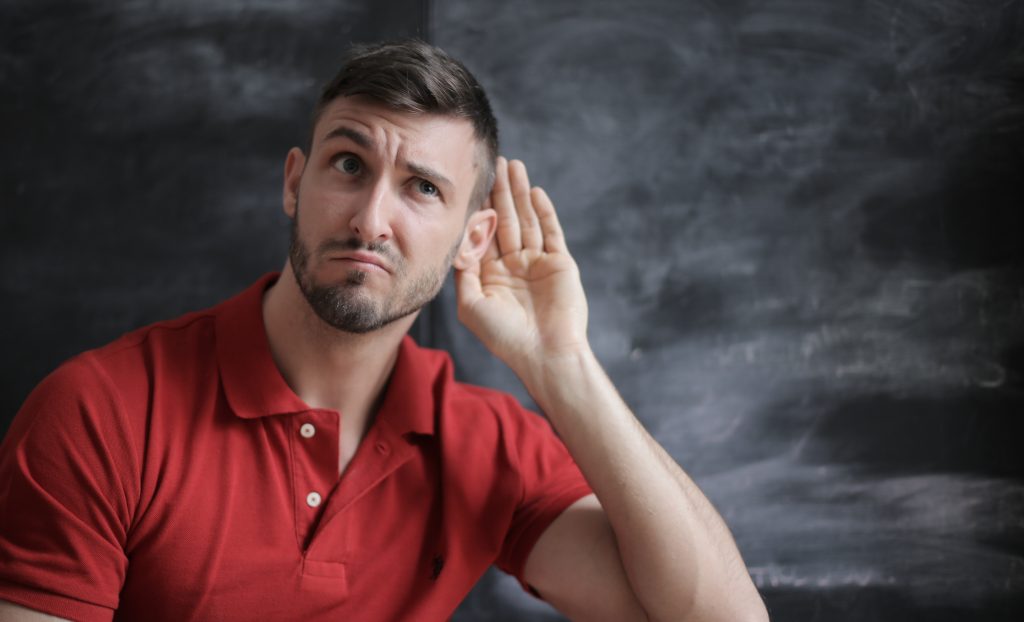 Men trying to hear a voice.